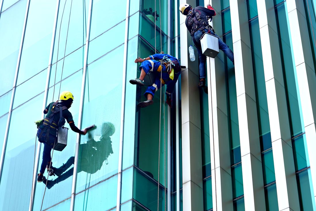Specialist operatives cleaning the glass facade of a tall building